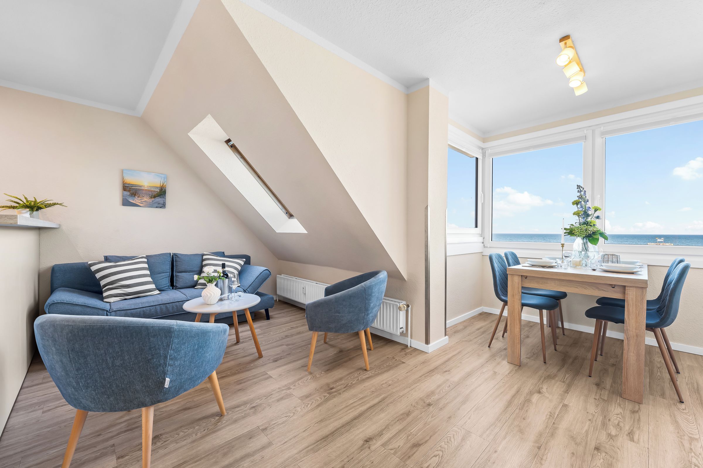 Een moderne woonkamer met een bank, stoelen, een eettafel en uitzicht op zee.