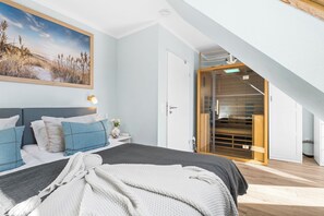 A bedroom with a bed, pillows, a bedside table, a nightstand, a painting, and a closet with a sliding door. - Holiday Apartment Strandblick – Sea Views, Relaxation & Holiday Bliss (Schönberg (Holstein))