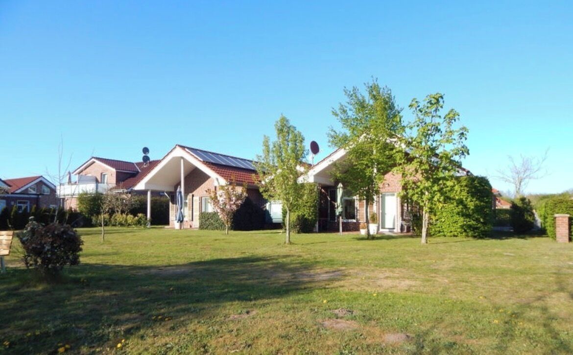 A residential area with houses, a grassy lawn, and trees.