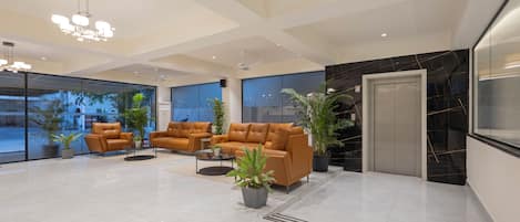 A spacious living area with leather sofas, a coffee table, and potted plants.