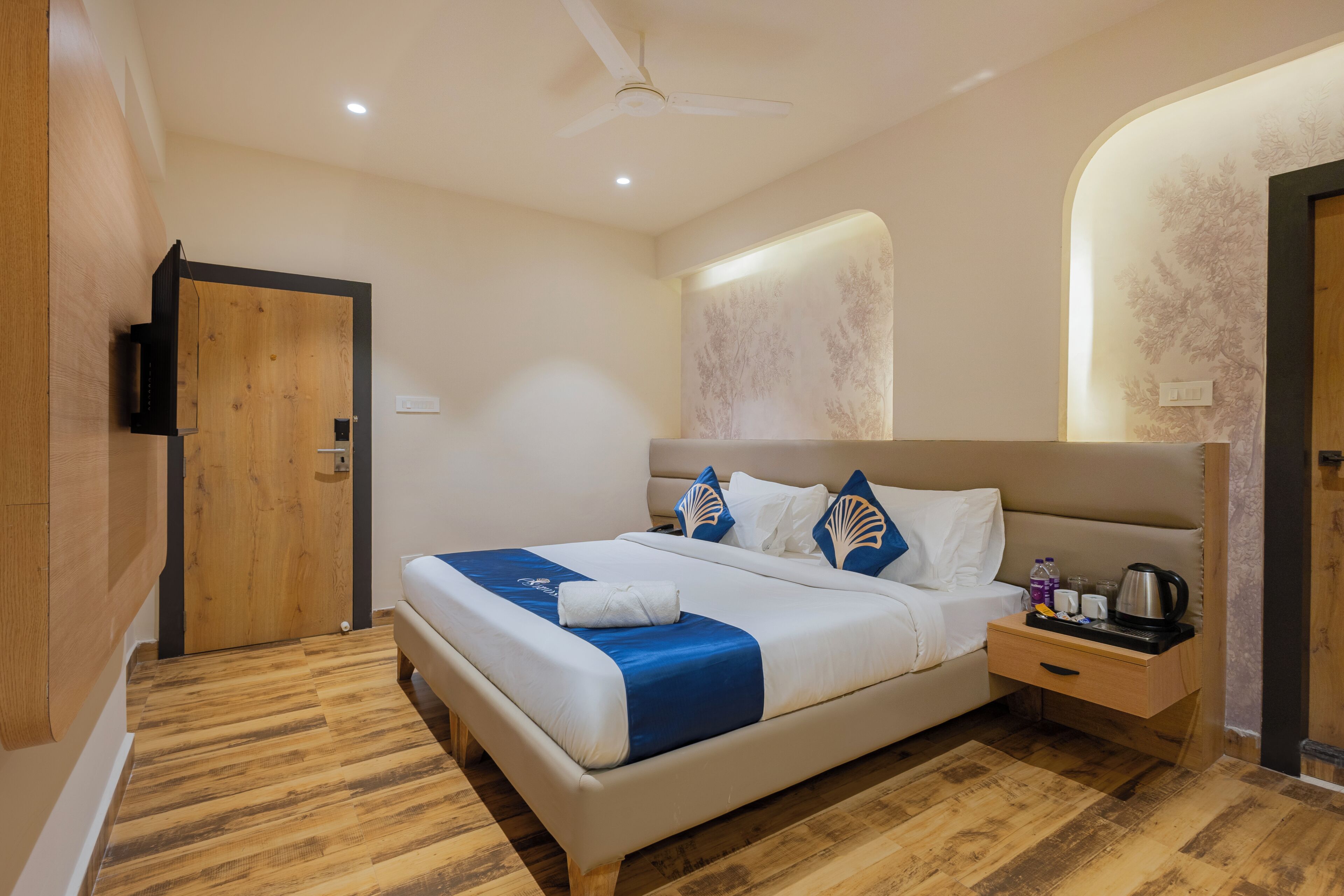 Habitació d'hotel amb llit, taulella de nit i ventilador de sostre.