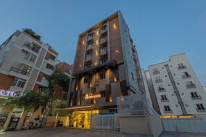 Un edificio de hotel de varios pisos con diseño moderno, que presenta una entrada destacada con un letrero de neón.