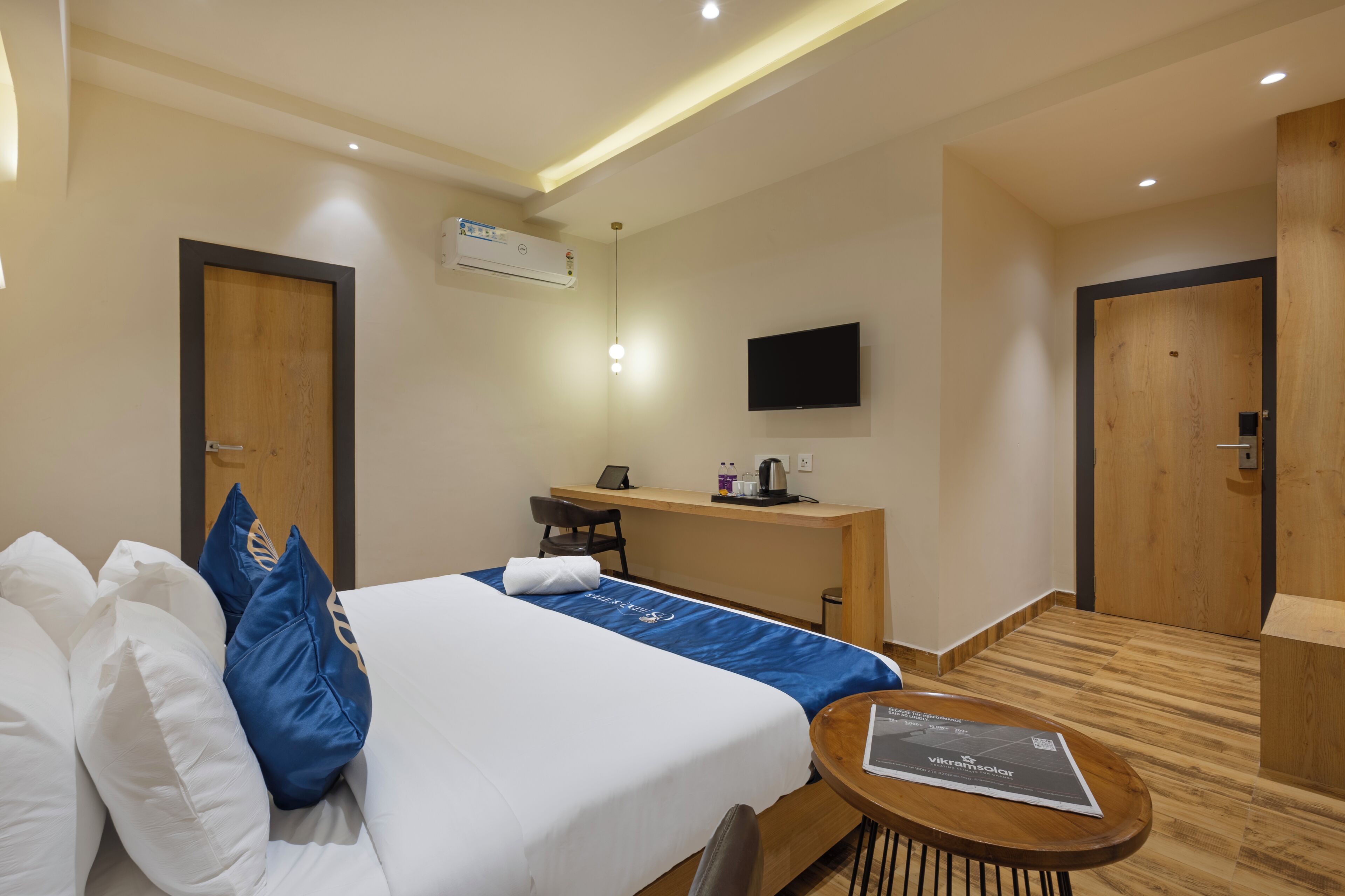 A hotel room with a bed, a desk, a TV, and a small table.