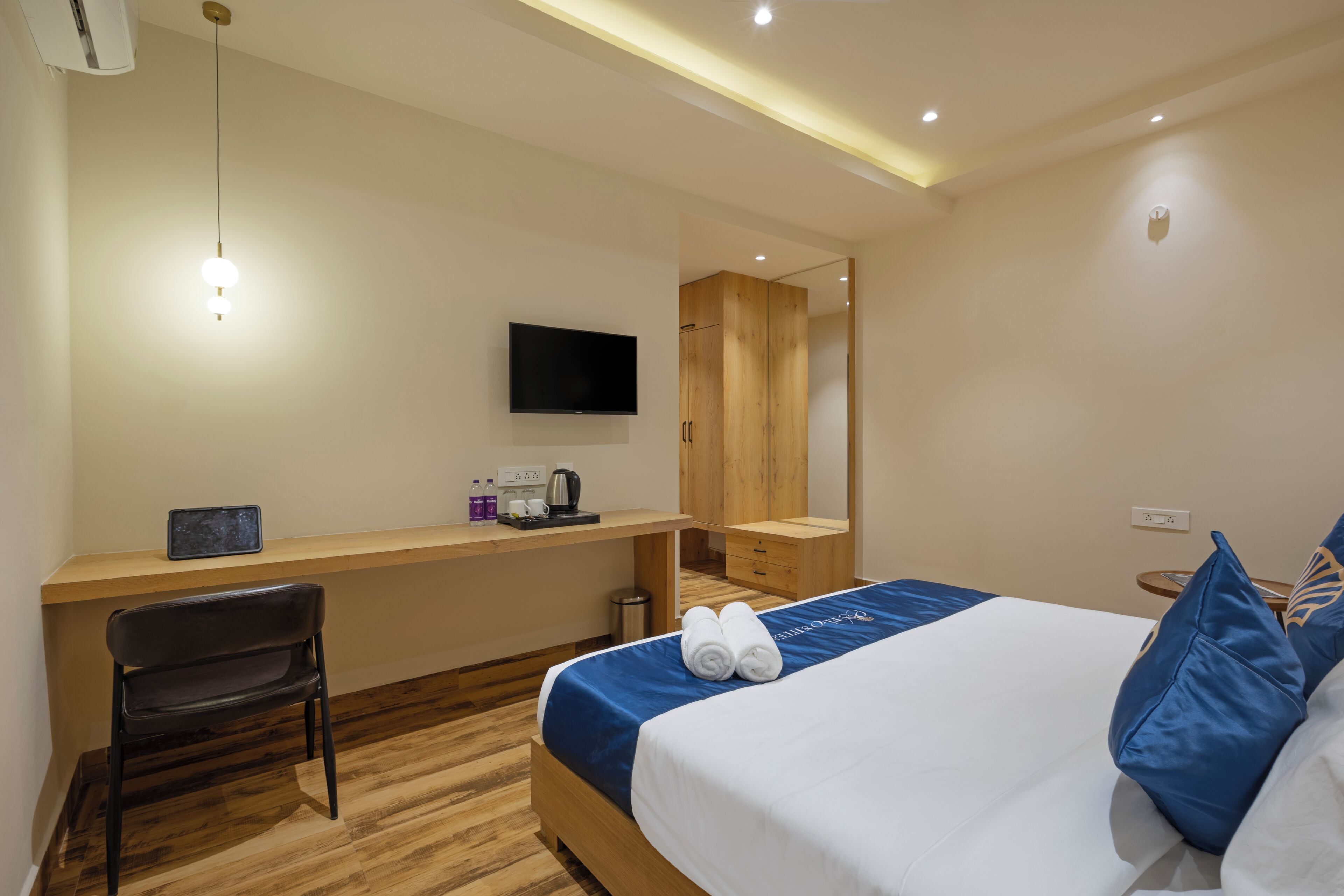 Ein Hotelzimmer mit einem Bett, einem Schreibtisch, einem Sessel, einem Fernseher und einem Spiegel.