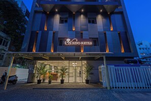 Un bâtiment moderne avec une enseigne indiquant « ESEVO SUITES », ce qui laisse supposer qu’il s’agit d’un hôtel ou d’un établissement proposant des hébergements.