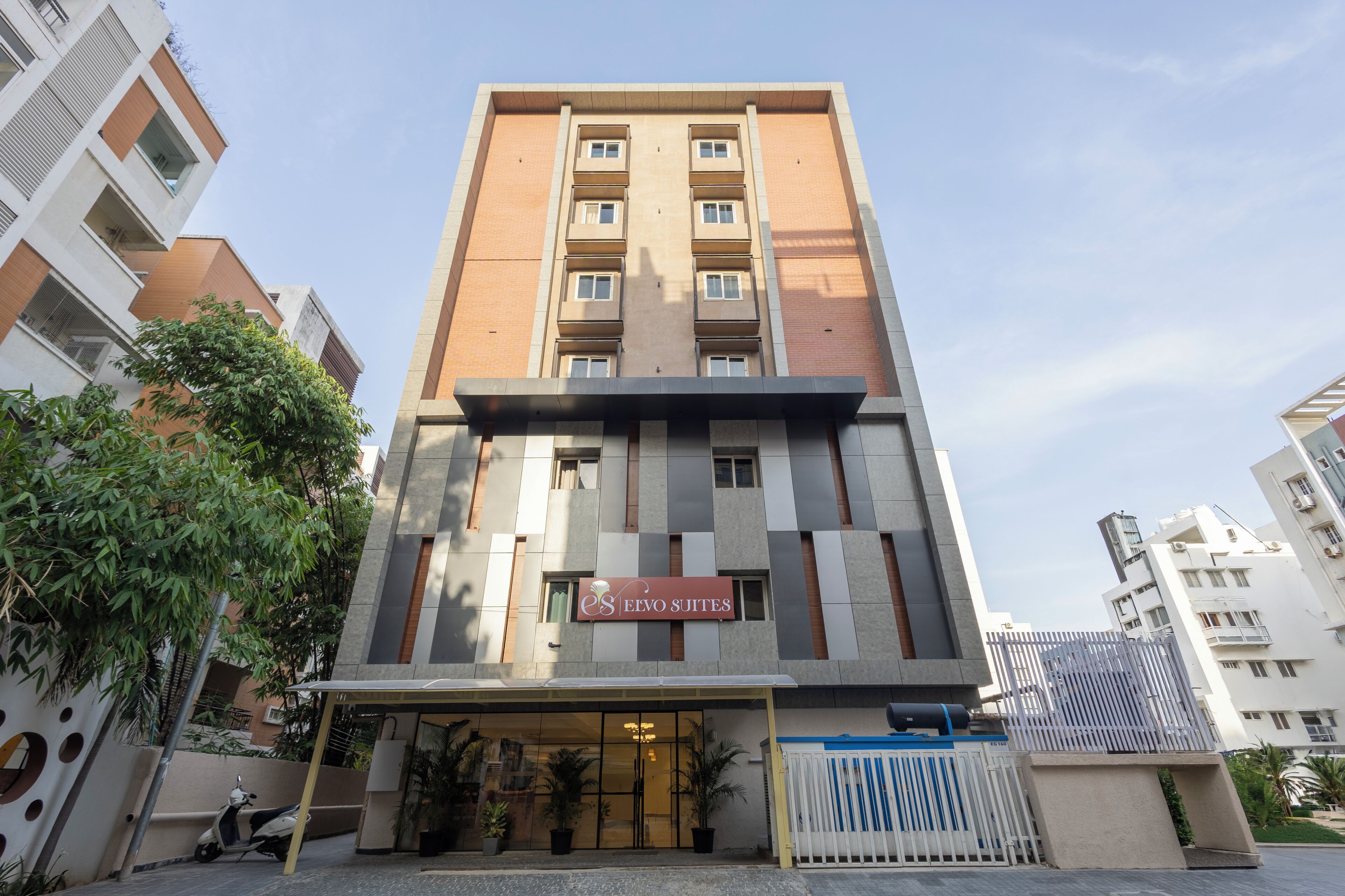 Un edificio de hotel de varios pisos con fachada moderna, una entrada visible con toldo y un letrero que indica el nombre del hotel.