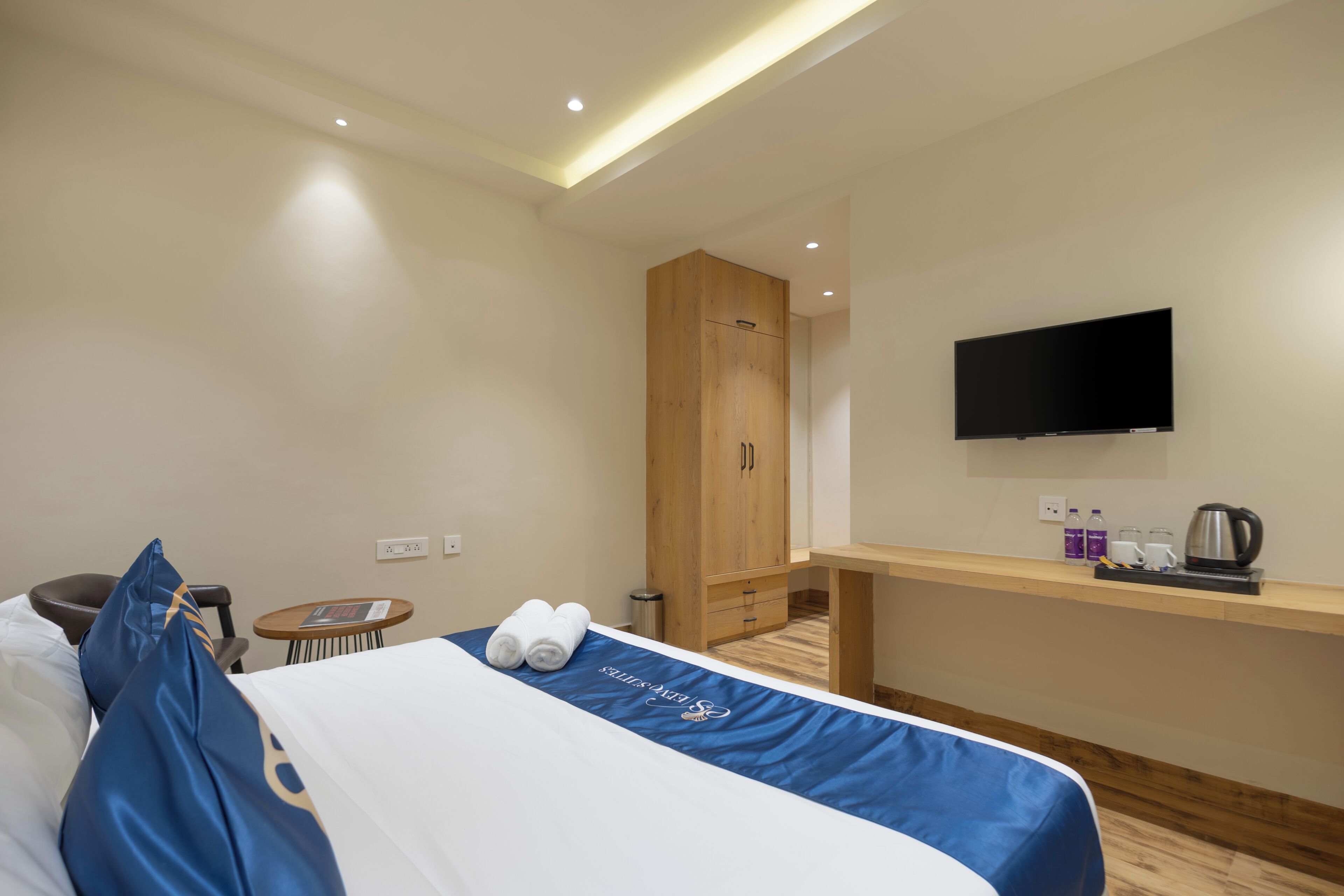 A hotel room with a bed, a desk, a television, and a wardrobe.