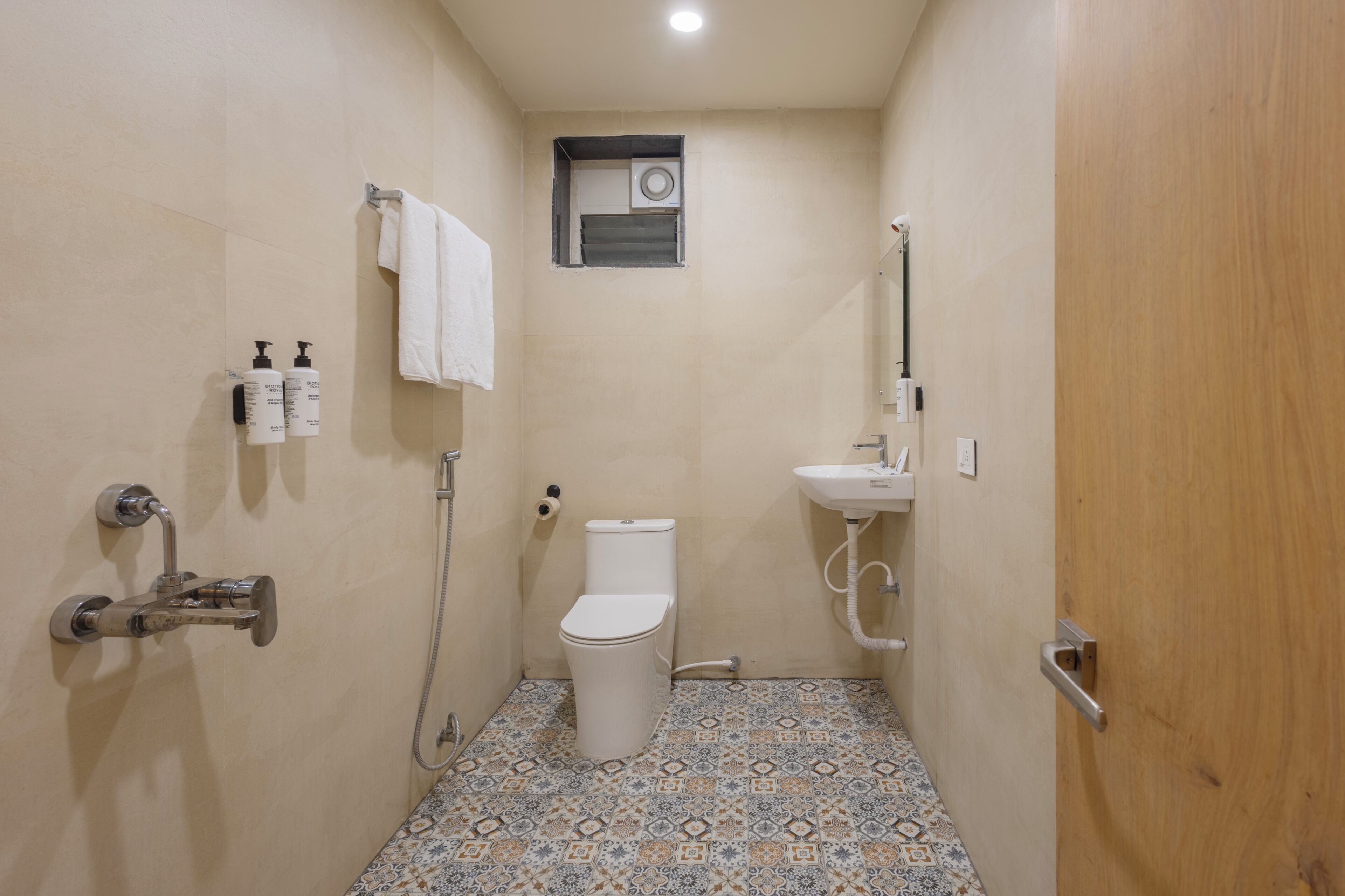 A small bathroom with a toilet, a sink, and a shower. There are two bottles of toiletries on the wall.
