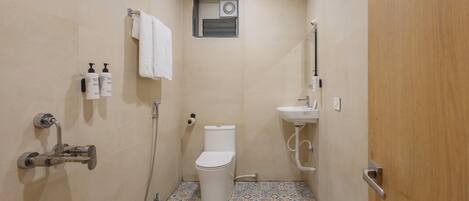 A small bathroom with a toilet, a sink, and a shower. There are two bottles of toiletries on the wall.