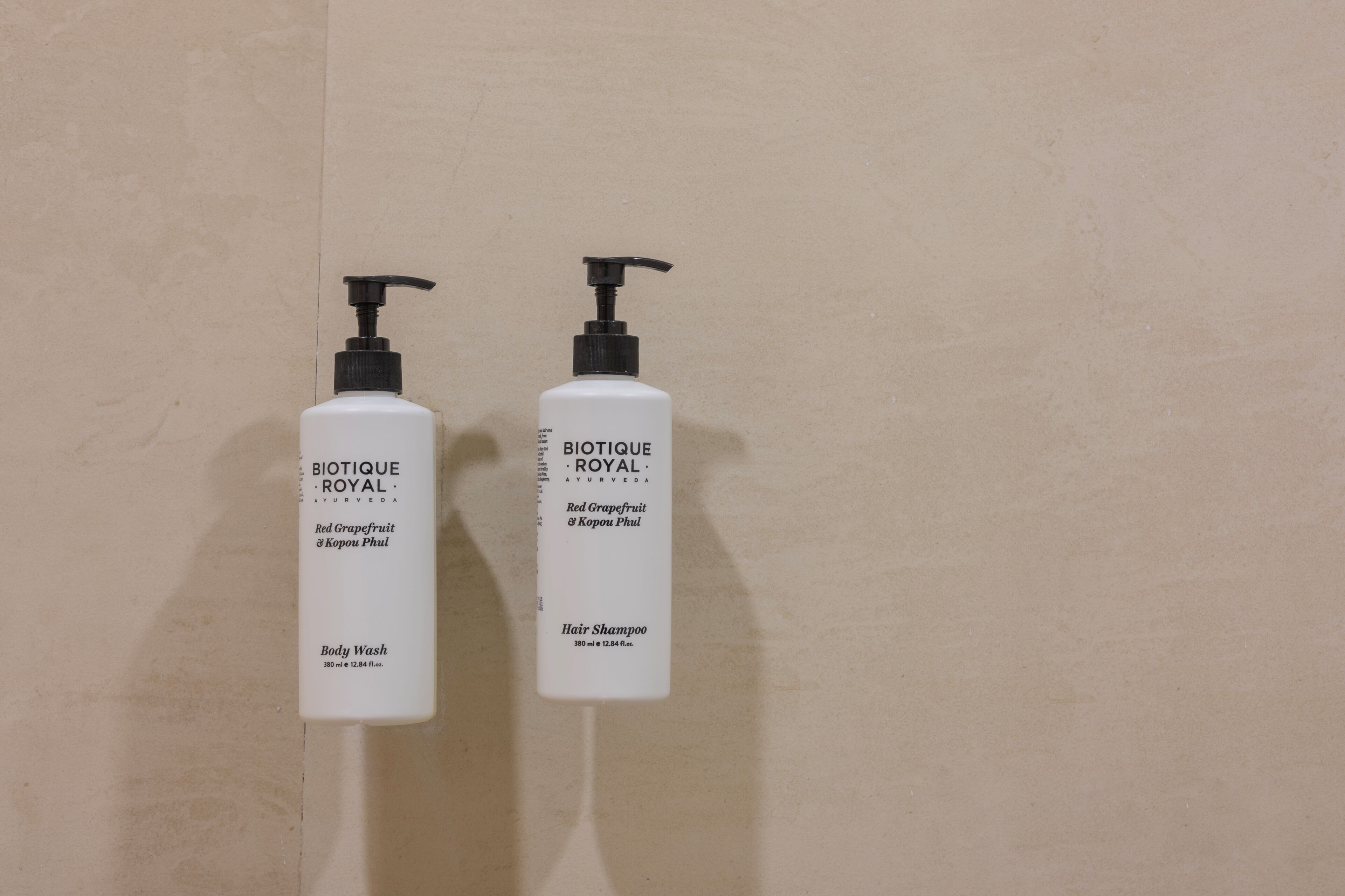 Duas embalagens brancas de Biotique Royal para lavar cabelo e corpo, em frente a uma parede lisa.
