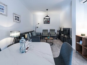 A modern living room with a marble table, grey sofas, a coffee table, and a television. - Apartment  by Interhome (Nerja)