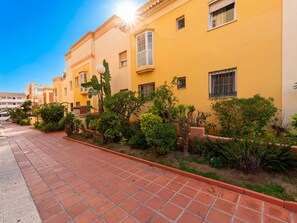 A row of yellow buildings with a paved walkway in front. - Apartment  by Interhome (Nerja)