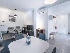 A modern living room with a dining area, a flat-screen TV, and a built-in air conditioning unit. - Medina Torrecilla Beach by Casasol by Interhome (Nerja)