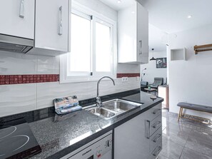 A modern kitchen with a double sink, stainless steel appliances, and a window providing natural light. - Apartment  by Interhome (Nerja)