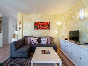 A living room with a sofa, a coffee table, a TV, and a painting on the wall. - Ladera del Mar 32 by Casasol by Interhome (Nerja)