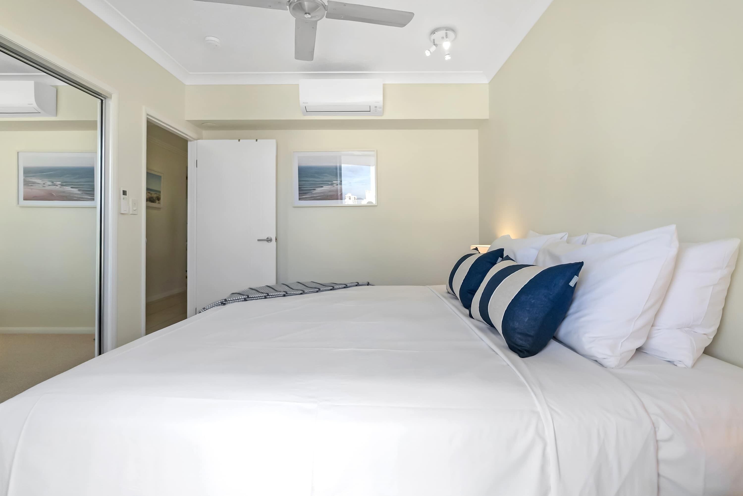 Une chambre à coucher avec un lit, un ventilateur de plafond, une fenêtre donnant sur un beau paysage et une porte.