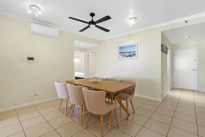 A dining area with a table and chairs, a ceiling fan, and a picture on the wall. - Seaview Escape—Scenic Views, Pool and Prime Location (Cairns City)