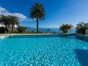 A clear blue pool with a view of the sea and palm trees. - Apartment  by Interhome (Nerja)