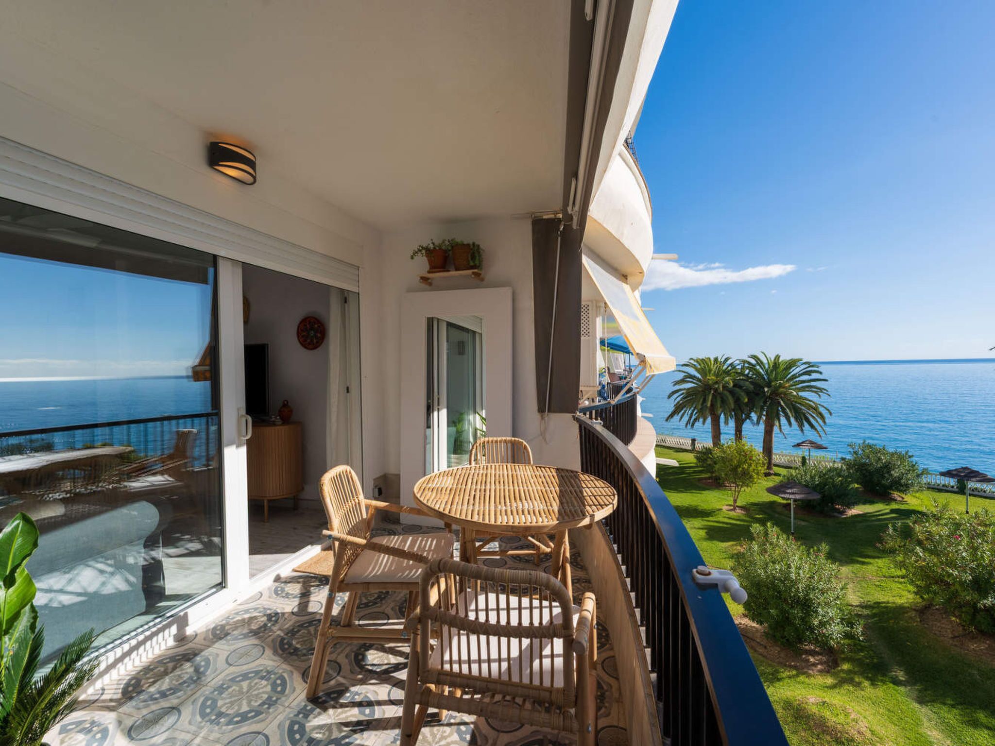 A balcony with a table and chairs, overlooking a sea view.