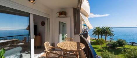 A balcony with a table and chairs, overlooking a sea view.