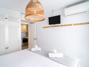 A hotel room with a bed, a television, an air conditioning unit, and a wicker lamp. - Acapulco Playa 302 by Casasol by Interhome (Nerja)