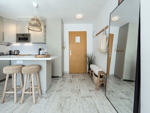 A modern kitchen with a central island, bar stools, and a wooden bench. - Apartment  by Interhome (Nerja)