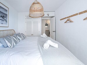 A bedroom with a bed, a hanging light fixture, a wardrobe, and a towel rack. - Apartment  by Interhome (Nerja)