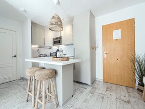 Eine moderne Küche mit Kochinsel, Barhocker und Holztür.