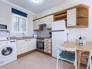 Uma cozinha compacta com máquina de lavar, forno e área de jantar com mesa e cadeiras.