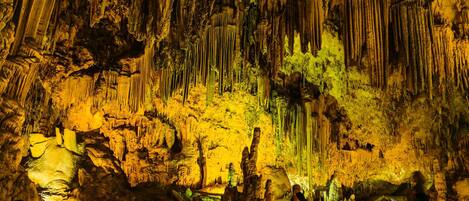 Een grot met stalactieten en -stalagmieten, verlicht door kunstlicht.