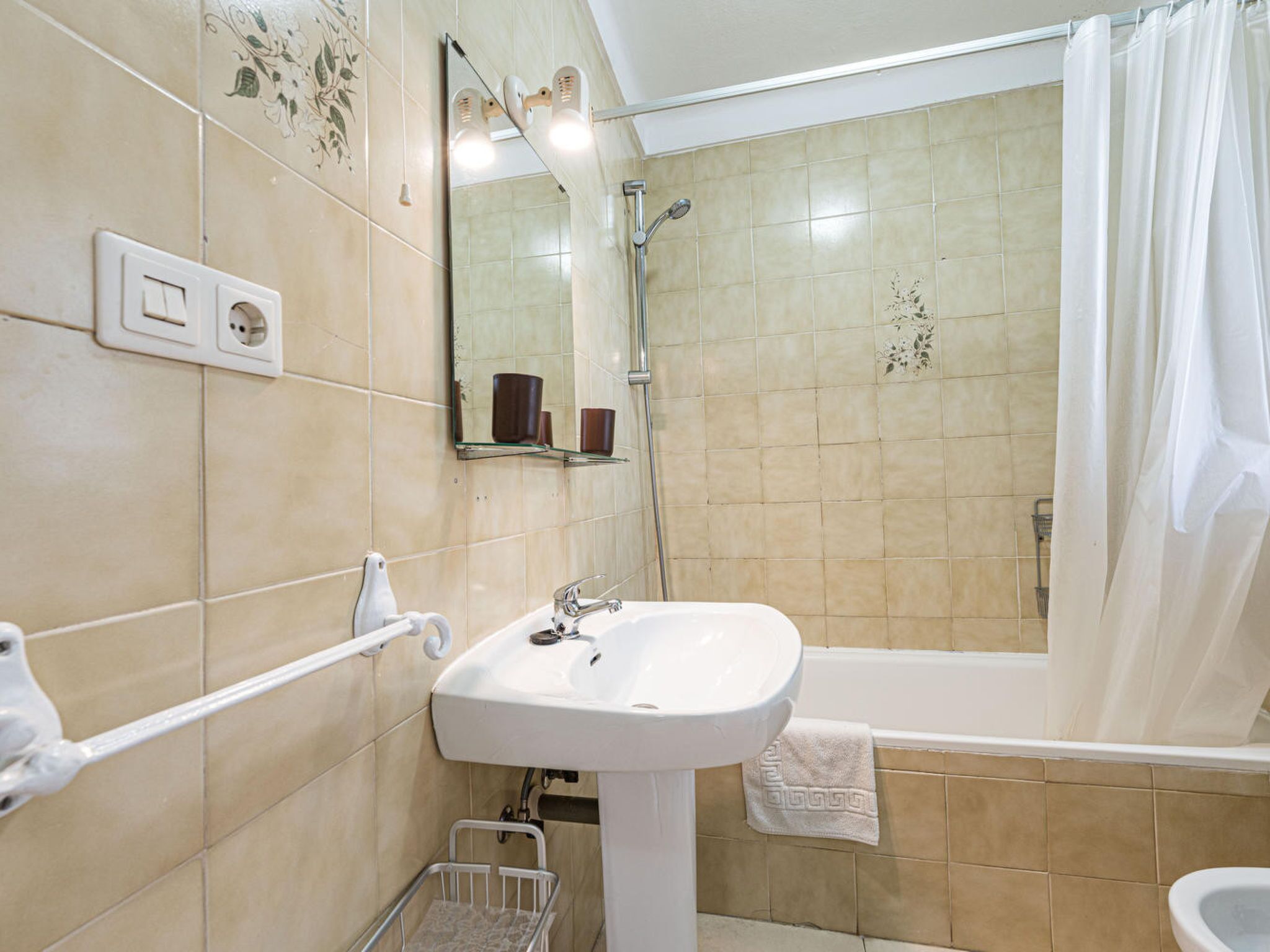 A bathroom with a white sink, a shower, and a toilet.