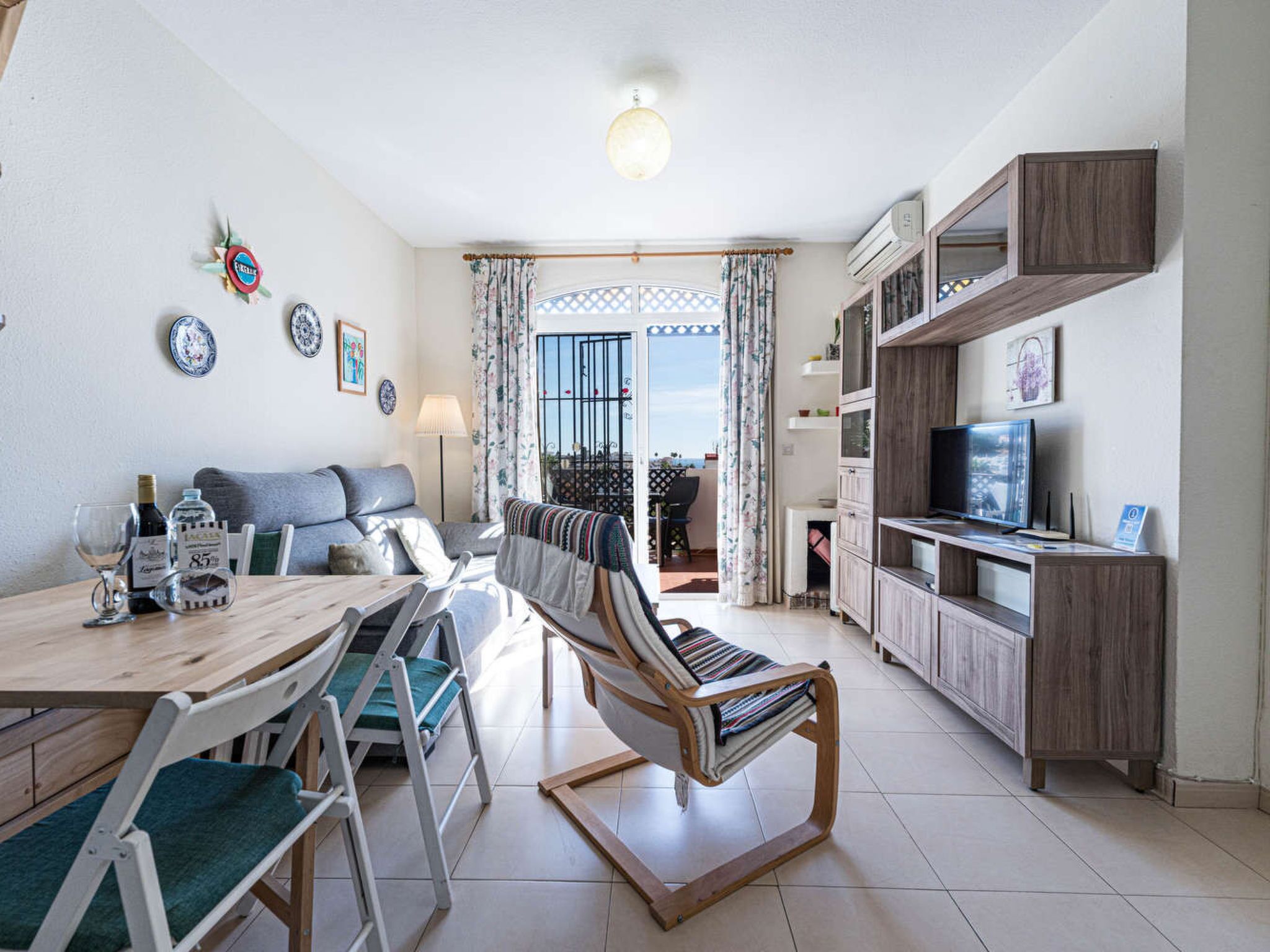 Ett kompakt bostadsutrymme med en matplats, soffa, TV och en balkong med utsikt.