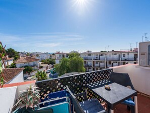 Eine Terrasse mit Tisch und Stühlen mit Blick auf ein Wohngebiet mit Gebäuden und blauem Himmel.