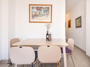 A dining area with a table, chairs, a framed painting, and a vase with flowers. - Toboso  1C Torrecilla Beach Paradise by Casasol by Interhome (Nerja)
