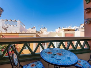 A balcony with a tiled table and chairs, overlooking a cityscape with buildings and a clear sky. - Toboso  1C Torrecilla Beach Paradise by Casasol by Interhome (Nerja)