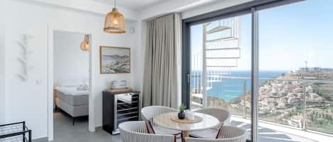 Uma sala de estar moderna com área de jantar, janelas amplas e vista para o mar.