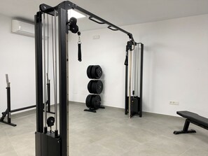 Ein Fitnessraum mit Gewichtstrainingsgeräten, einer Hantelbank und einem Wand-Squat-Rack.