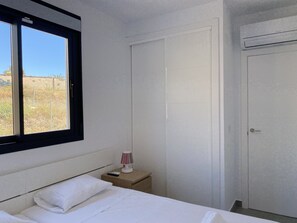 A bedroom with a bed, a nightstand, a lamp, and a window. - Penthouse Balcon del Mar Deluxe 3 by Casasol by Interhome (Nerja)