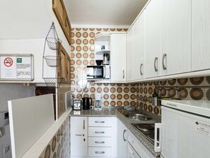 A compact kitchen with white cabinets, a microwave, a coffee maker, and a sink. - Carabeo 45 Studio by Casasol by Interhome (Nerja)