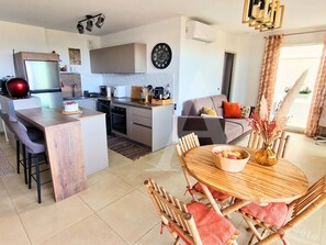 A modern kitchen with a central island, a dining area with wooden furniture, and a living room with a sofa and a coffee table. - 104 / T2 RES DE STANDING, CLIM, PARKING (Sète)