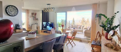 Um espaço de estar moderno com cozinha, sala de jantar e uma grande janela com vista para o exterior.