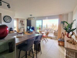 A modern living space with a kitchen, dining area, and a large window offering a view of the outdoors. - 104 / T2 RES DE STANDING, CLIM, PARKING (Sète)