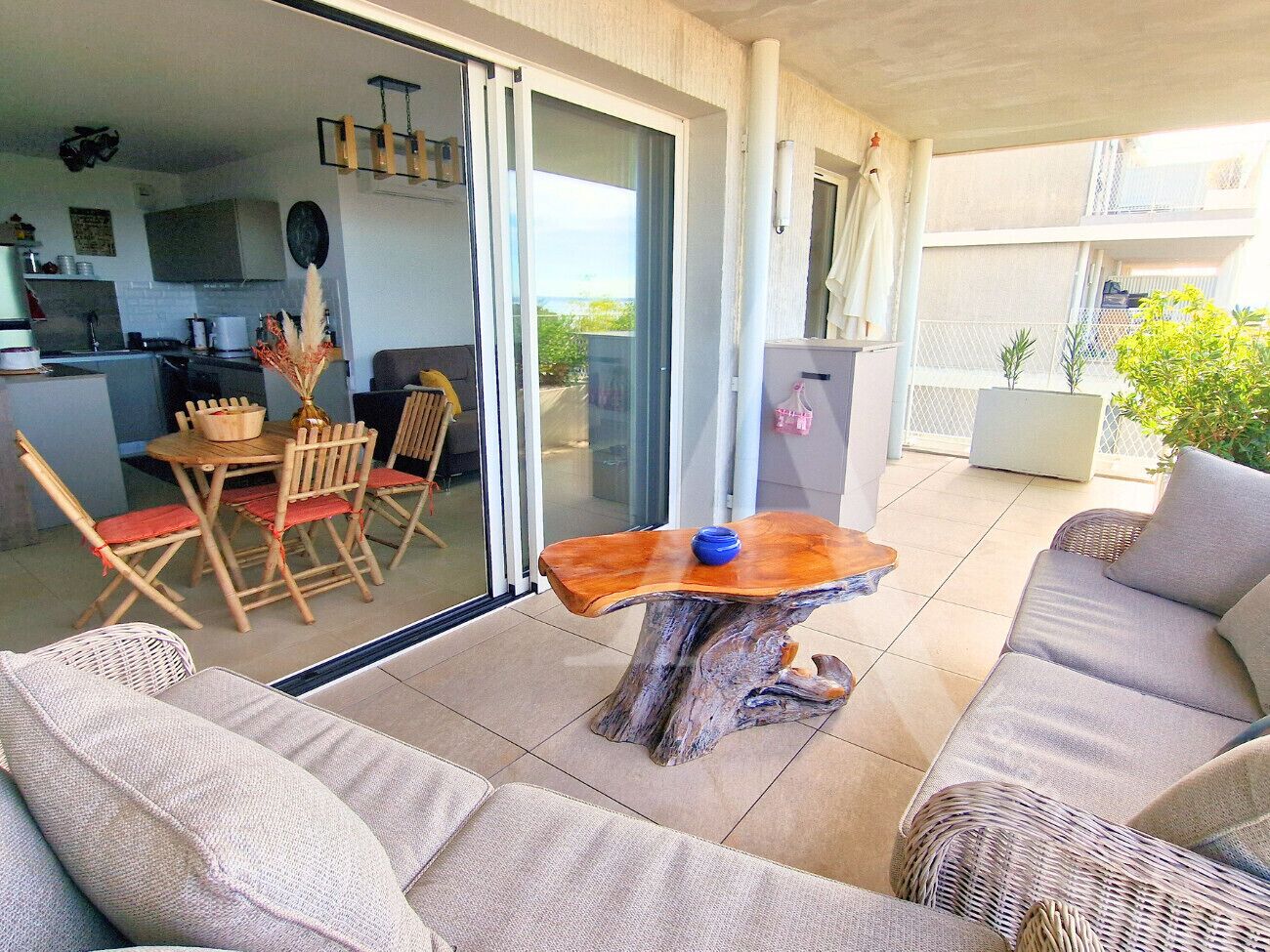 Un espacio al aire libre con mesa de madera y mobiliario de mimbre.