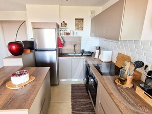 A compact kitchen with a refrigerator, stove, and sink. There is a wooden countertop and a rug on the floor. - 104 / T2 RES DE STANDING, CLIM, PARKING (Sète)