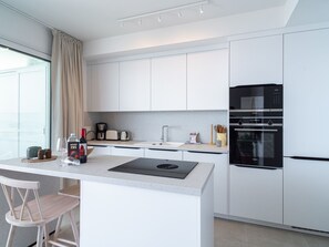 A modern kitchen with white cabinetry, a black refrigerator, and a built-in oven. - Apartment  by Interhome (La Axarquía/ Torrox)