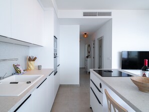 Een moderne keuken met witte kasten, een inbouwoven en een groot kookeiland.