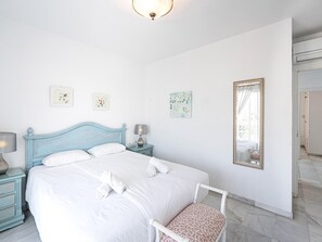 Ein Schlafzimmer mit einem Bett, einem Nachttisch, einer Lampe, einem Sessel und einem Spiegel.
