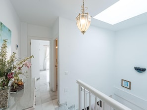 A hallway with a staircase, a hanging light fixture, and a wall-mounted decorative item. - Fuentesol 15 Casa Lindblad by Casasol by Interhome (Nerja)