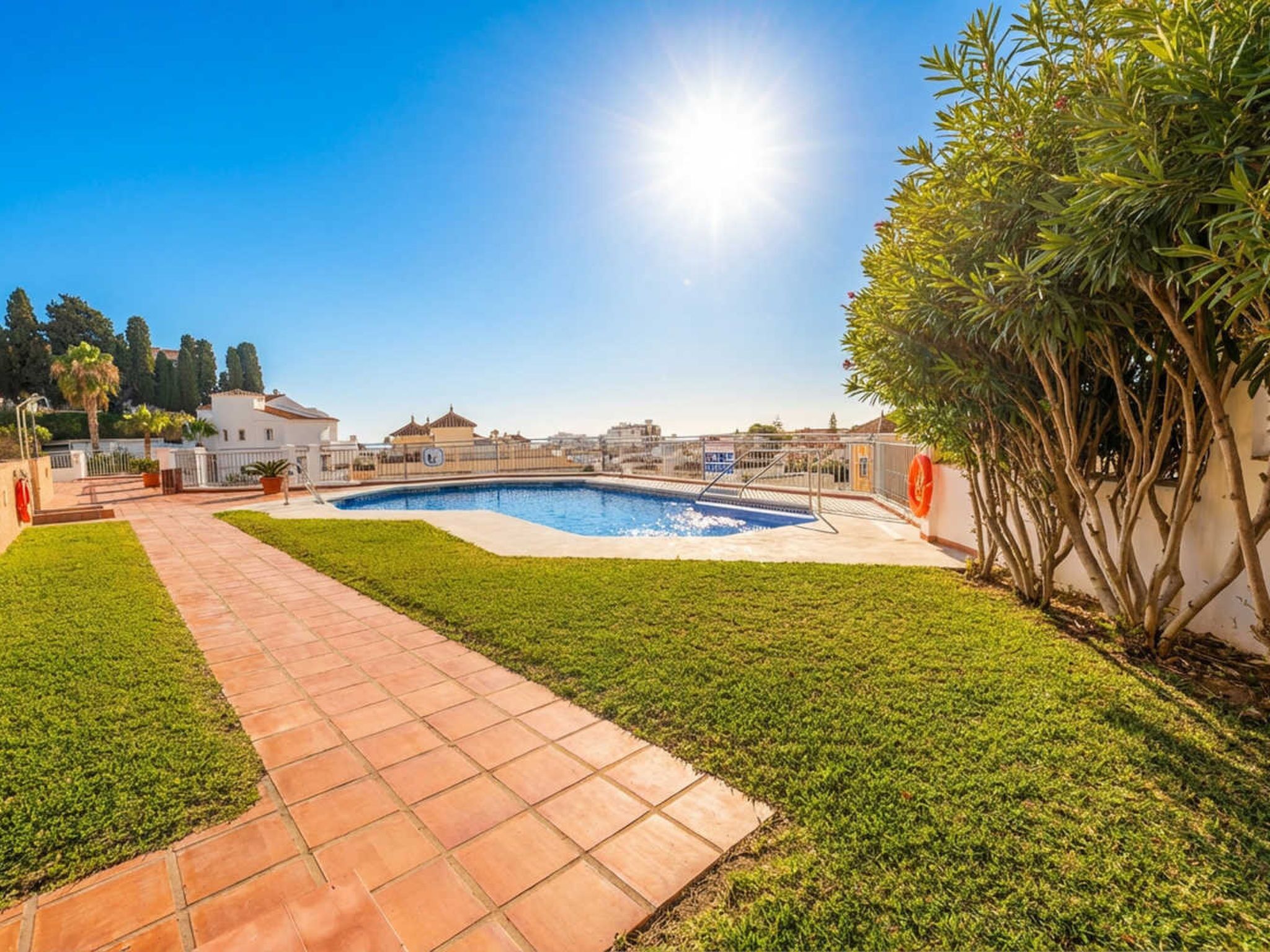 Una piscina amb terrassa enrajolada i cel serè.