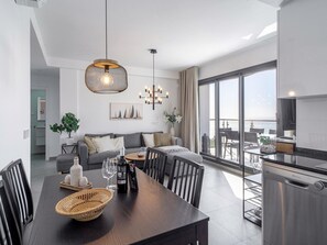 Une cuisine moderne dotée d’un four encastré et d’un coin repas avec une table et des chaises en bois foncé.